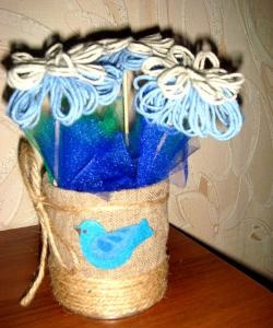 Flores hechas de hilos en un jarrón casero.