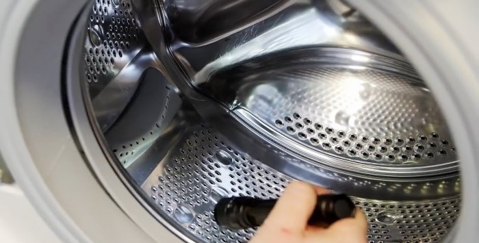 How to remove small objects caught behind the drum from a washing machine